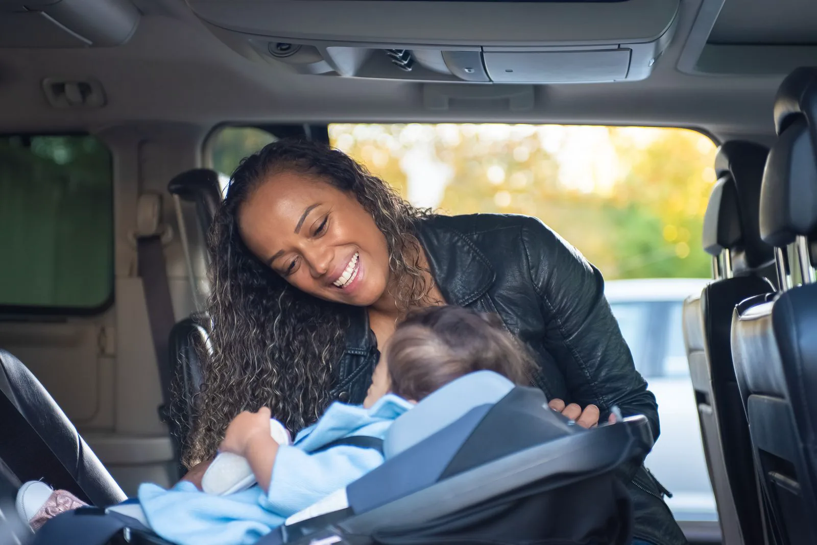 Mutter neben ihrem Baby im Kindersitz eines Autos