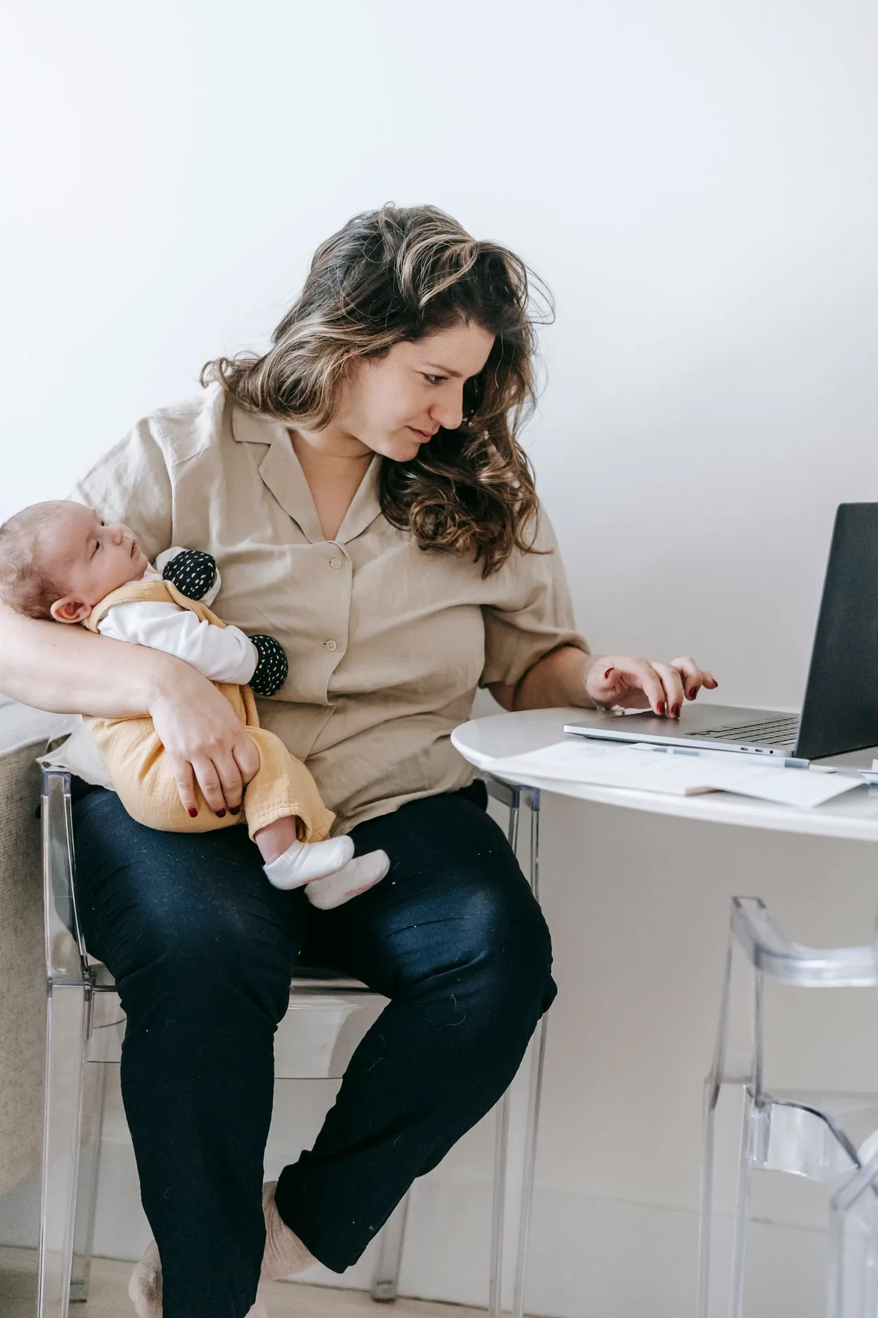 Mutter mit Baby vor einem Laptop zu Hause