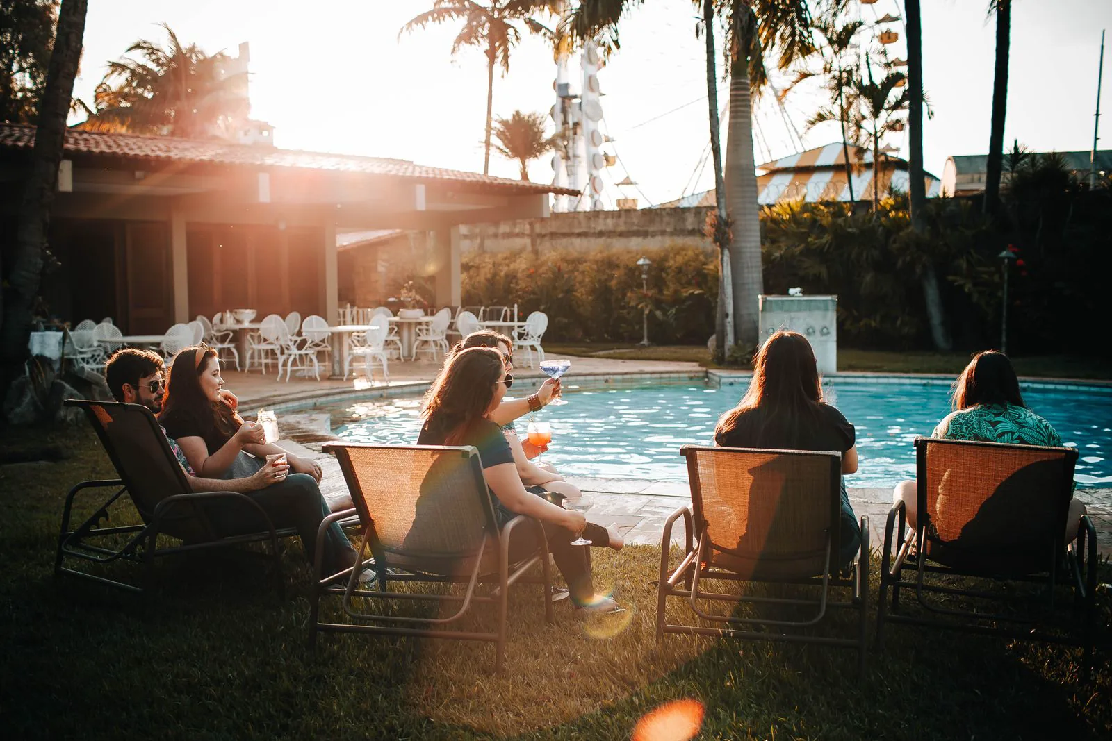 Menschen sitzen gemeinsam auf Liegen am Pool